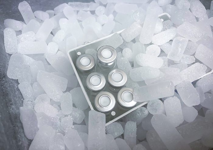 Closeup on vials with crimp caps placed on dry ice prepared for medical transport. Selected focus.