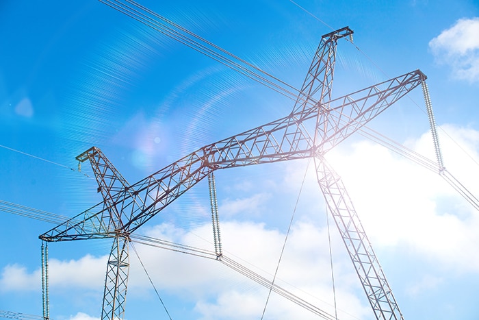 electricity transmission pylon silhouetted against blue sky at dusk